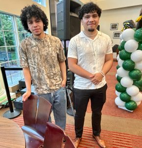 Two young men stand side-by-side smiling.