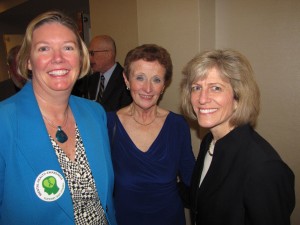 Three smiling women pose for a photo at an event.