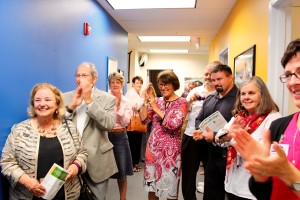 A group of people are standing in a hallway and clapping.