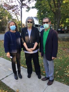 Three masked people stand outside, next to a sidewalk. The image appears to be related to mental health services.