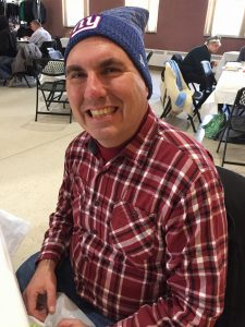 NewBridge-client Steven Henry smiles, wearing a NY Giants hat.