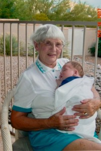 Older woman lovingly cradles a newborn baby in a blanket. 