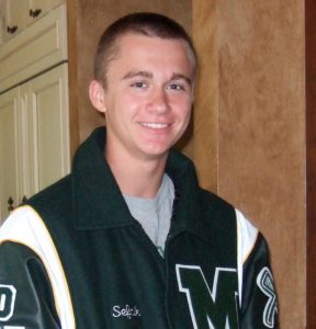A smiling young man in a letterman jacket.