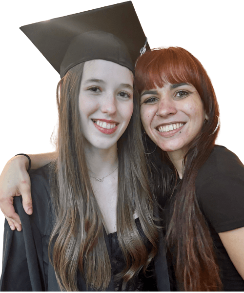 The student wears a graduation cap and gown, a hand rests on her shoulder.