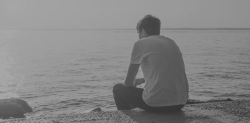 A man sits by the water